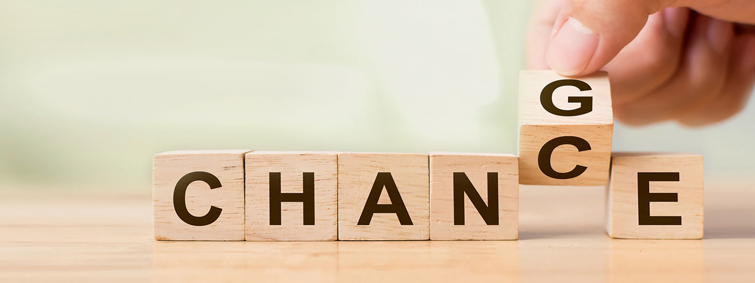 karriere_header_chance Hand legt einen Holzbaustein mit dem Buchstaben 'G' an eine Reihe von Holzbausteinen, die das Wort 'CHANCE' bilden.