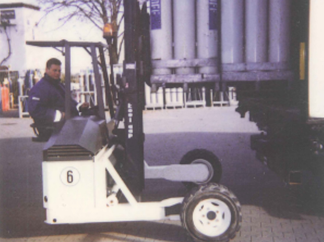 35_jahre_Schwanteland_beitrag_web4 Gabelstapler hebt ein Gasflaschenbündel mit mehreren vertikal stehenden Gasflaschen auf gepflastertem Boden