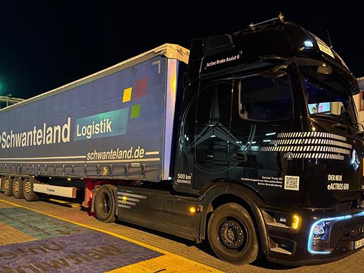 Schwarzer E-LKW mit Auflieger und Aufschrift 'Schwanteland Logistik schwanteland.de' steht nachts auf einem Parkplatz